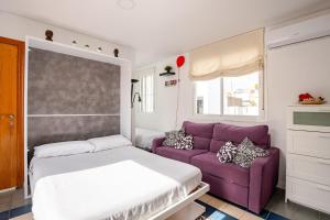 a bedroom with a purple couch and a bed at Ático la Azotea con terraza PRIVADA in Seville