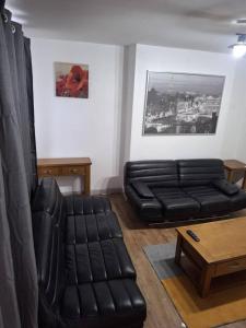 a living room with a black leather couch and a coffee table at Kilvington Crib in Sheffield +9 photos