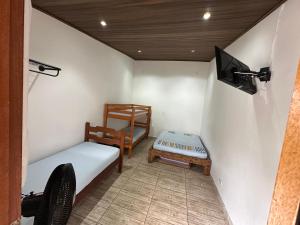a small room with a bed and a tv at QUARTOS Praia do Tombo Guarujá in Guarujá