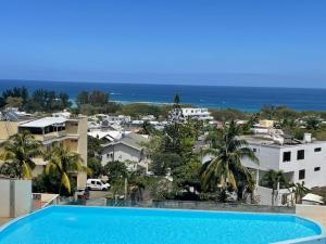 a large blue swimming pool with a view of a city at Sunset Ocean View Apartment in Flic-en-Flac