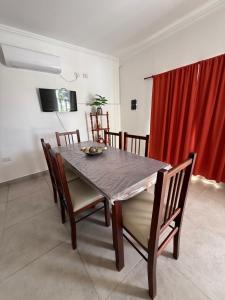 Una mesa de comedor con sillas y una cortina roja. en Departamento en alquiler temporario, en Fernández 4 fotos más