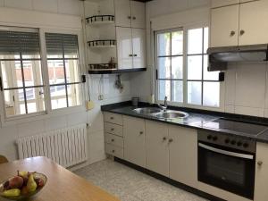 a kitchen with white cabinets and a bowl of fruit on a table at Casa Cancelas in Santiago de Compostela