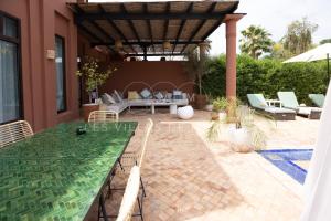 a patio with a table and chairs and an umbrella at Dar Nadim sur le Golf de Samanah in Marrakesh