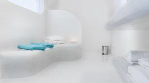 a white bathroom with white walls and white towels at Maregio Suites in Oia