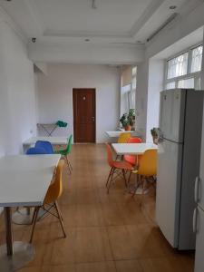 a room with tables and chairs and a refrigerator at Хостел in Almaty