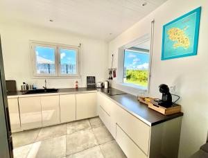 a kitchen with white cabinets and a window at Chez Valérie et Patrick in Le Diamant