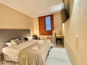Un dormitorio con una cama y un escritorio y una ventana. en Júbilus Rooms, en Toledo