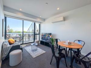 Modern 2B Apt with Views Near Swinburne University في ملبورن: غرفة معيشة مع طاولة وأريكة وتلفزيون