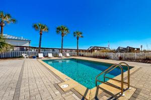 a swimming pool with palm trees and a fence at Veranda 101 in Fort Walton Beach