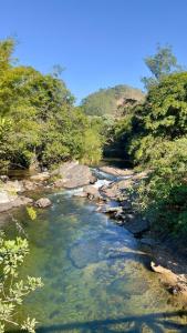 un arroyo de agua con rocas y árboles en Casa Vale dos Peões Lumiar 2, en Nova Friburgo
