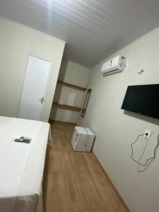 a small room with a white bed and a wooden floor at Pousada Caminho do Paraíso in Jijoca de Jericoacoara