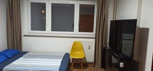 a bedroom with a bed and a yellow chair and a window at Apartement Saint Louis Train Station- EuroAirport- Basel in Saint-Louis