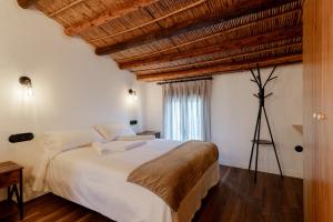 a bedroom with a large white bed with a wooden ceiling at Casa Rural Mas dels Fumeros in Useras +20 photos