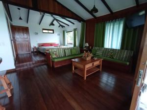a living room with green furniture and a bed at Aloha Chirripo Lodge in Convento