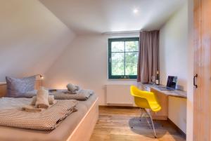 due letti in una stanza con una scrivania e una sedia gialla di Ferienhaus Bootshaus in Nadelitz a Putbus