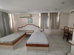 a room with two beds and a table and chairs at Slaass flat in Manaus