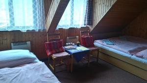 a small room with two beds and a table and chairs at Penzión Encián in Mýto pod Ďumbierom