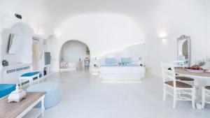 a white room with a bed and a table at Maregio Suites in Oia
