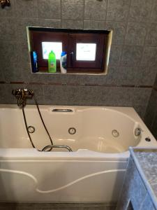a white bath tub in a bathroom with two windows at MHome AGIOS ATHANASIOS in Palaios Agios Athanasios