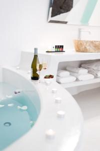 a bathroom with a tub and glasses of wine at Maregio Suites in Oia