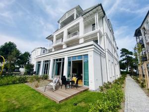 a large white building with a deck and chairs at Ferienwohnung Luxus Sonnensuite in der Strandvilla Charlotte Binz in Binz