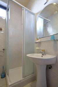 La salle de bains est pourvue d'une douche et d'un lavabo. dans l'établissement Apartments Rosemary, à Lucija