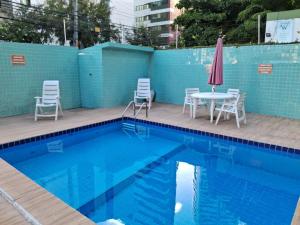 a pool with chairs and a table and an umbrella at Espaço Jeito de Casa Hospedagem em Quarto Compartilhado in Recife