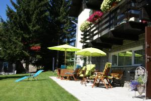 eine Gruppe von Stühlen und Sonnenschirmen auf einer Terrasse in der Unterkunft Pension Arabela in Harrachov