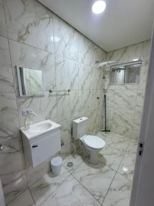 a white bathroom with a toilet and a sink at Recanto Martins in Ipojuca +7 photos