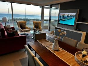 Una sala de estar con una mesa y un televisor. en BOUTIQUE LUMIERE FRENTE al MAR con vista a los atardeceres 2 dormitorios 3 baños cocina definida 2 balcones cochera y amenities Un verdadero lujo, en Punta del Este