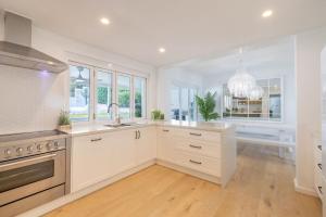 a kitchen with white cabinets and a sink at Cloud Nine, 18 Wynne Cres - heated pool, waterviews, beach in Corlette