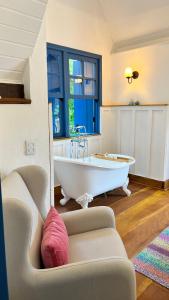 a bath tub in a room with a couch at Provence Cottage in Camanducaia