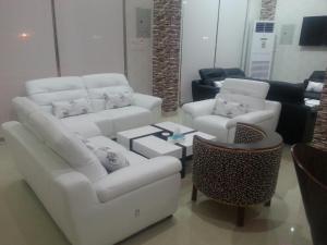 un soggiorno con divani bianchi e tavolo di Lara Al Jawf Hotel Apartments a Sakakah