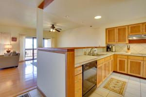 a large kitchen with wooden cabinets and a living room at Kailua-Kona Condo with Resort Access and Ocean View! in Kailua-Kona