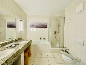 ein Badezimmer mit zwei Waschbecken und einer Badewanne und einer Toilette in der Unterkunft Ferienwohnung Binzer Seeblick Haus Jahreszeiten Binz in Binz + 16 Fotos