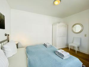ein Schlafzimmer mit einem Bett, einem Spiegel und einem Stuhl in der Unterkunft Ferienwohnung Binzer Seeblick Haus Jahreszeiten Binz in Binz