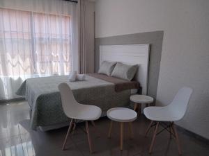 a bedroom with a bed with two tables and two chairs at Baksman's Retreat in Soweto