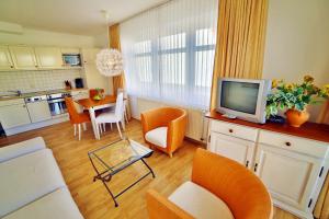 ein Wohnzimmer mit einem TV und einem Tisch mit Stühlen in der Unterkunft Ferienwohnung Binzer Strandgut im Haus Jahreszeiten Binz in Binz