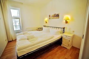 ein großes weißes Bett in einem Zimmer mit Fenster in der Unterkunft Ferienwohnung Binzer Strandgut im Haus Jahreszeiten Binz in Binz