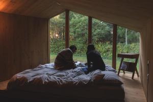 two women sitting on a bed in a room with windows at Earthboat Hakuba in Hakuba
