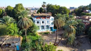 a white house with palm trees in front of it at BAYT ZAINA - Nubian hospitality house in Aswan