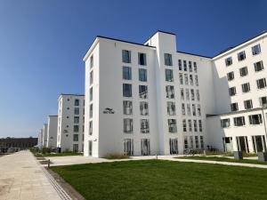 a row of white buildings with grass in the foreground at Ferienwohnung Ruhepol im Haus Zudar Prora in Binz