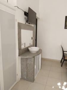 a bathroom with a sink and a tv on a wall at Casa Enna in Isla Mujeres