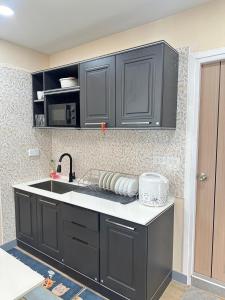 a kitchen with black cabinets and a sink at Dertera Poolvilla เดอเทร่าพูลวิลล่า หาดใหญ่ in Hat Yai