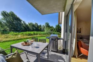 a patio with a table and a grill in a house at Ferienwohnung Haubentaucher 25 im Wreecher Idyll Rügen by ruyastay in Putbus