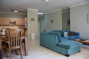a living room with a blue couch and a table at Paragon Apartment 6 - Bring your own linen. in South West Rocks