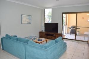 a living room with a blue couch and a tv at Paragon Apartment 6 - Bring your own linen. in South West Rocks