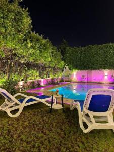 a chair and a swimming pool with lights at Standalone Villa in New Cairo, Private swimming pool and modern furniture in Cairo