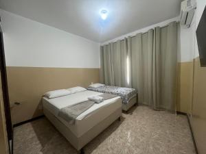 two beds in a small room with a window at Pousada Aconchegante in Jequié