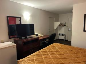 a hotel room with a bed and a desk with a television at Metro Inn in Calgary